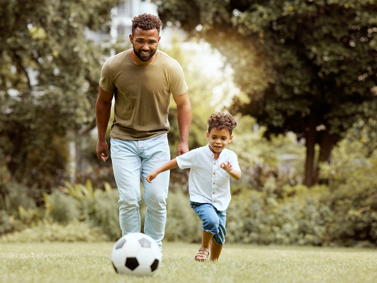 Father and son playing soccer in a park