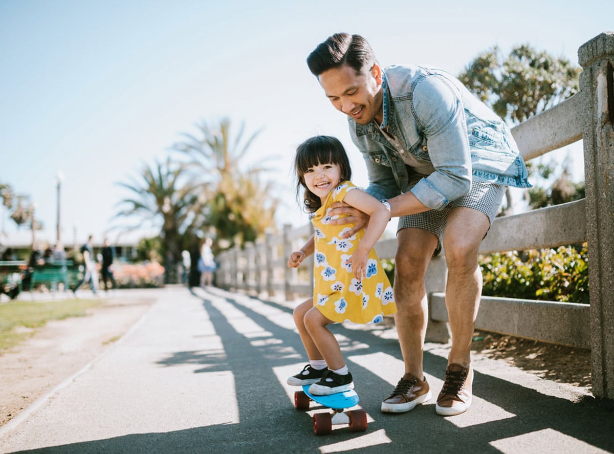 Dad teaching daughter how to skateboard